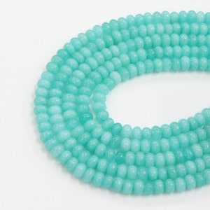 May include: A strand of turquoise blue round beads. The beads are smooth and have a slightly glossy finish.