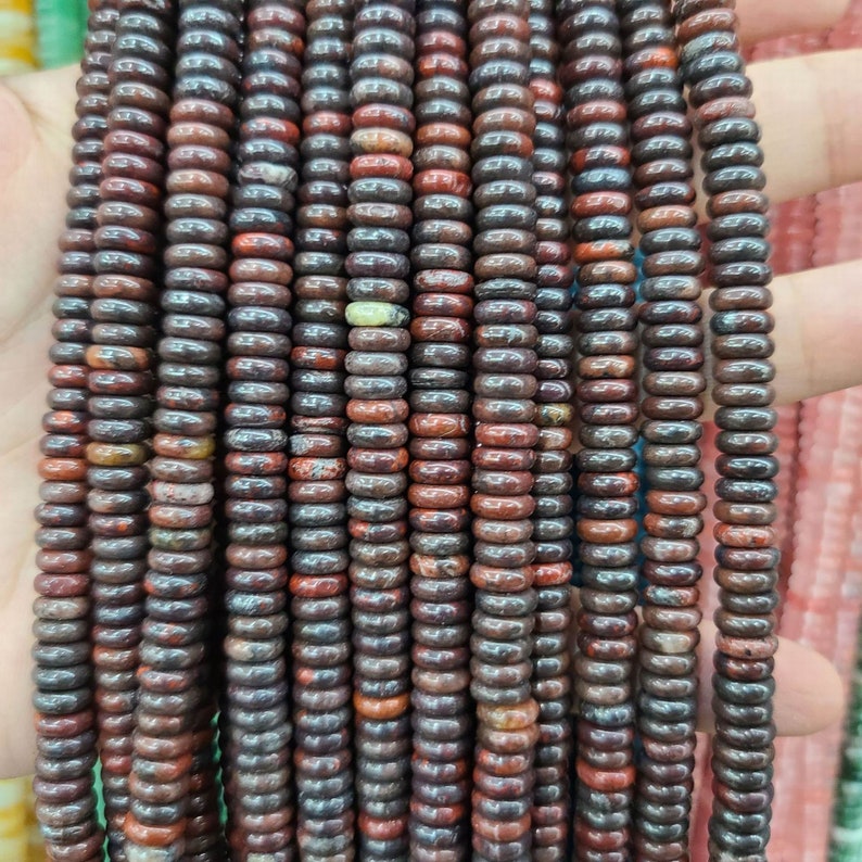 Pu&ograve; includere: Una collana di perline di pietre preziose rosse e marroni, ogni perlina &egrave; rotonda e ha una forma leggermente irregolare. Le perline sono infilate su un filo trasparente e sono pronte per essere utilizzate per la creazione di gioielli.