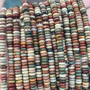 May include: A strand of colorful, round, gemstone beads. The beads are a mix of red, brown, green, and white. The beads are all about 1/2 inch in diameter.