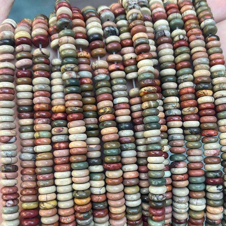 May include: A strand of colorful, round, gemstone beads. The beads are a mix of red, brown, green, and white. The beads are all about 1/2 inch in diameter.