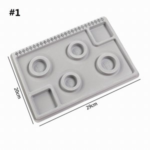 May include: Gray plastic ring sizing tool with four ring sizing circles and a ruler marked in sizes 1 to 40. The tool measures 29 inches by 20 inches.