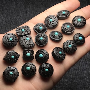 May include: A collection of 18 black wooden beads with turquoise inlay. Each bead features a different intricate design.