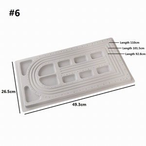 May include: White plastic beading board with multiple rows of holes and a curved section for making bracelets. The board measures 26.5 inches by 49.3 inches. The board has three different lengths marked: 110 cm, 101.5 cm, and 92.8 cm.