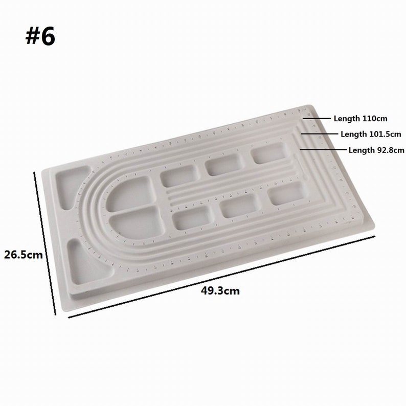 May include: White plastic beading board with multiple rows of holes and a curved section for making bracelets. The board measures 26.5 inches by 49.3 inches. The board has three different lengths marked: 110 cm, 101.5 cm, and 92.8 cm.