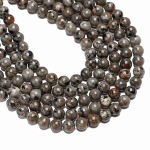May include: A strand of round, black and grey speckled beads. The beads are approximately 8mm in diameter.
