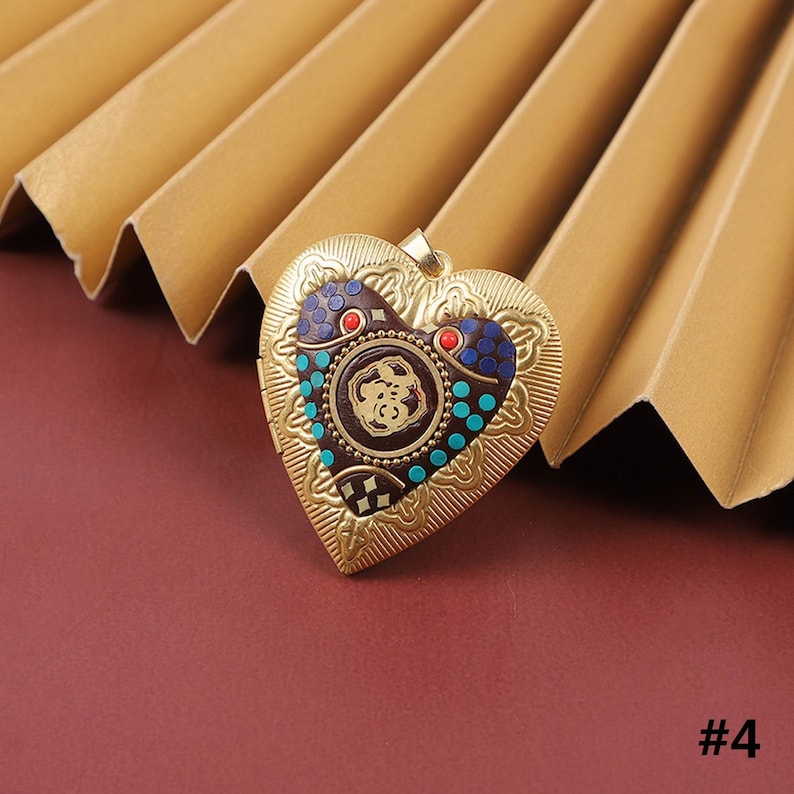 Puede incluir: Medall&oacute;n de coraz&oacute;n de oro con un dise&ntilde;o intrincado y colorido. El medall&oacute;n presenta un patr&oacute;n circular con acentos azules, rojos y dorados.