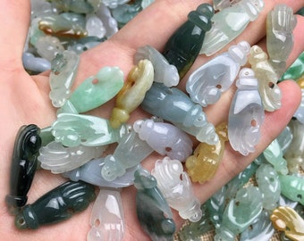 Puede incluir: Una colección de dijes de mano de jade en varios tonos de verde, blanco y azul claro. Los dijes están tallados en forma de mano con un agujero en la parte superior para enhebrar.