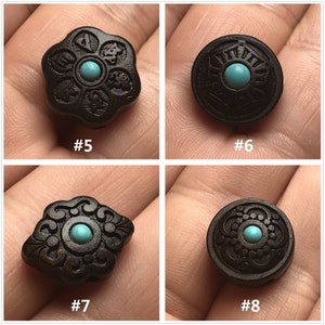 May include: Four black wooden beads with intricate carvings and turquoise accents. Each bead features a different design, including a flower, a circle, and two diamond shapes.