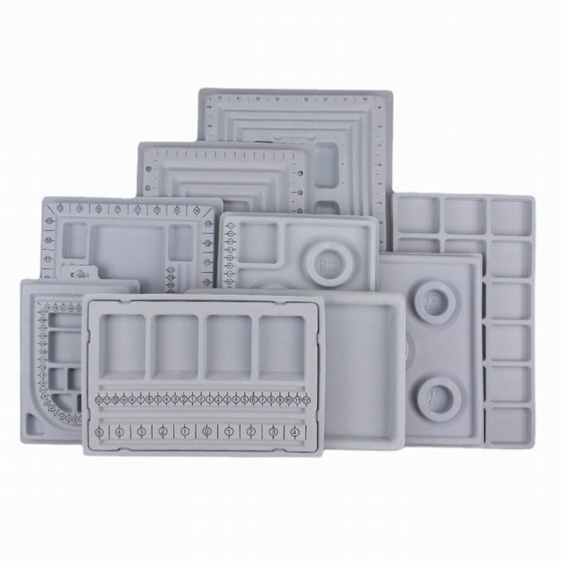 May include: Set of nine gray plastic trays with various compartments and sizing guides for jewelry making.