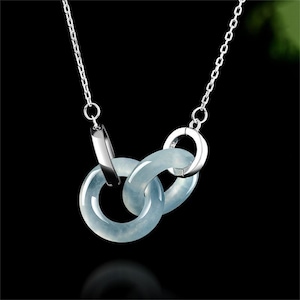 May include: A silver necklace featuring three interlocking rings of pale blue jade. The rings are connected by silver clasps and suspended from a delicate silver chain. The necklace is displayed against a black background.