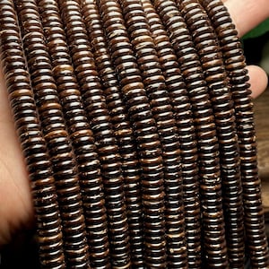 Puede incluir: Una hebra de cuentas de cáscara de coco marrón. Las cuentas son redondas y tienen un aspecto natural y rústico.