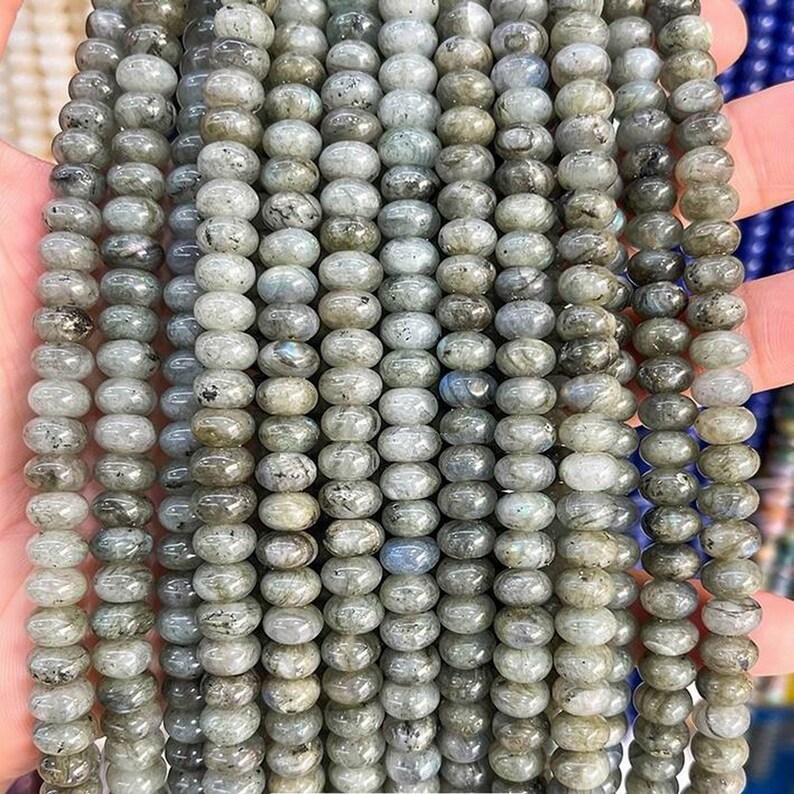 May include: A strand of round, gray labradorite beads. The beads have a smooth, polished finish and a subtle iridescent sheen.