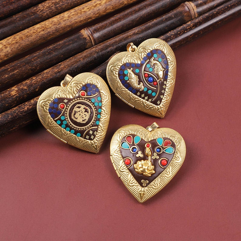 Puede incluir: Tres medallones de coraz&oacute;n de oro con dise&ntilde;os intrincados. Cada medall&oacute;n presenta un patr&oacute;n de esmalte colorido diferente con acentos azules, rojos y turquesa.
