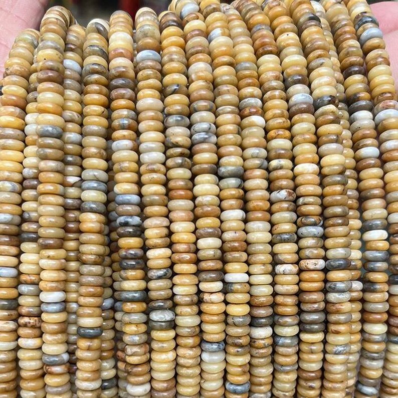 May include: A strand of round, yellow, brown, and white agate beads. The beads are approximately 6mm in diameter and have a smooth, polished finish.