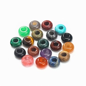 May include: Assortment of 18 colorful gemstone donut beads. Each bead has a hole in the center. The beads are made of various stones, including green, red, blue, purple, and brown.