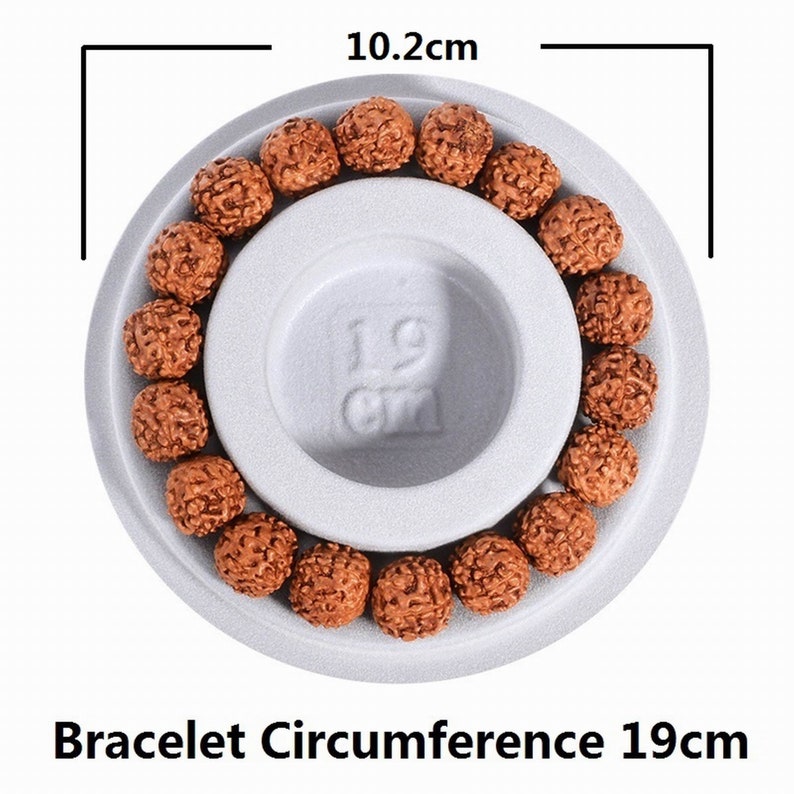 May include: A brown wooden bracelet with 19 beads, laid out on a white circular surface with a 19 cm diameter. The bracelet is 10.2 cm in diameter.