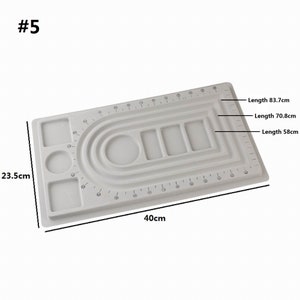 May include: White plastic jewelry making board with a ruler, circles, and squares for creating necklaces and bracelets. The board measures 23.5 inches by 40 inches.