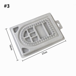 May include: Gray plastic jewelry making board with numbered circles around the edge and a grid of smaller squares in the center. The board measures 23 cm by 16 cm.