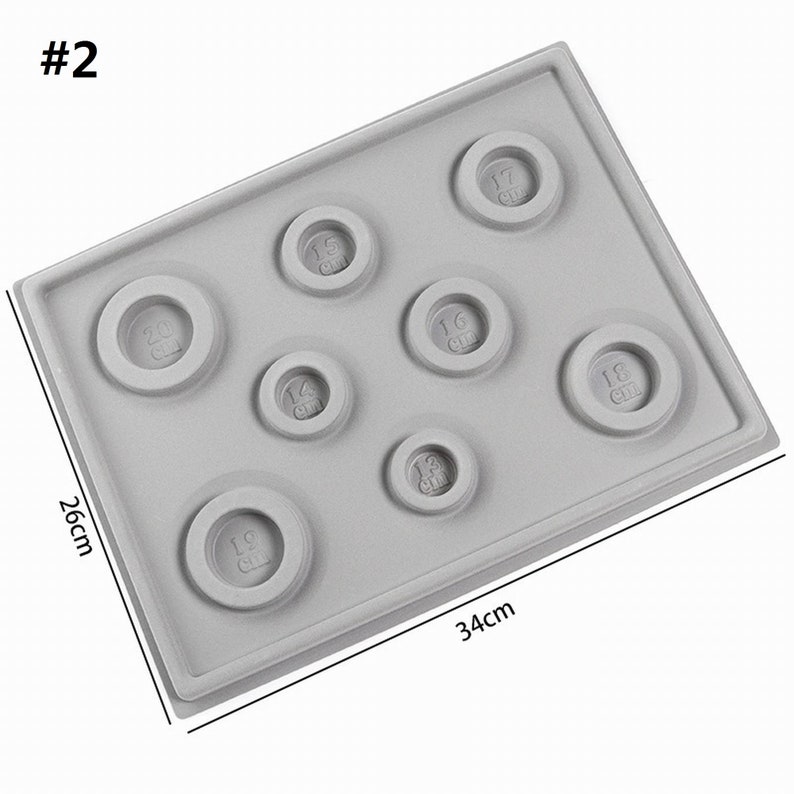 May include: A gray silicone mold with eight circular depressions of different sizes, labeled with their diameter in centimeters. The mold measures 26 cm by 34 cm.