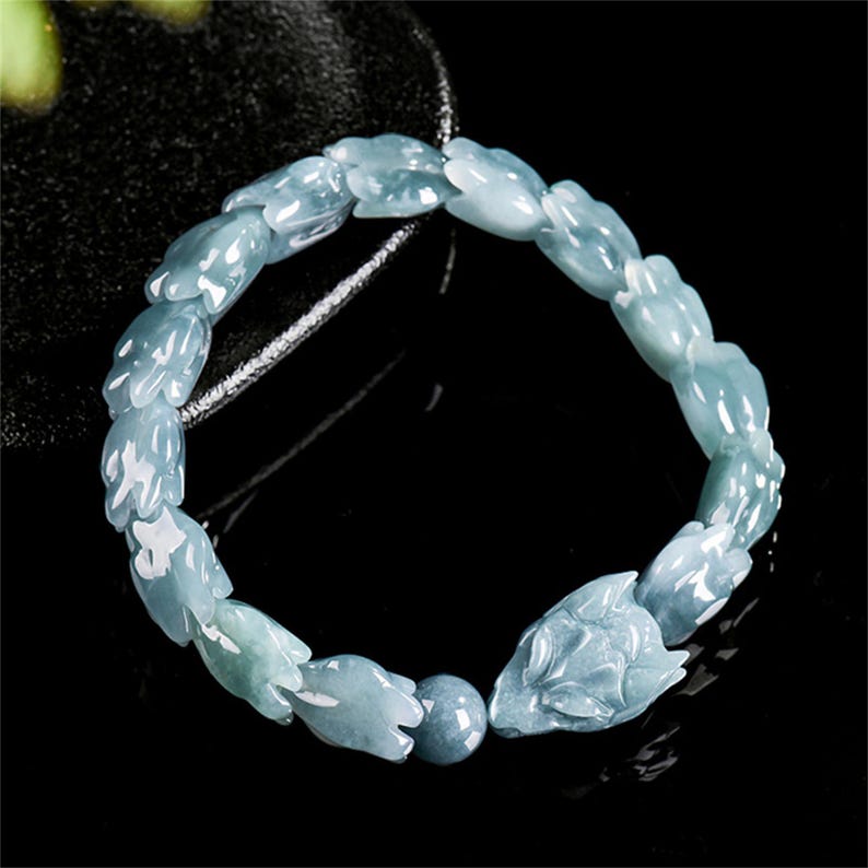 Puede incluir: Pulsera de jade azul claro con cuentas talladas en forma de flor y un cierre de cabeza de zorro. La pulsera est&aacute; ensartada en un cord&oacute;n oscuro. Una elegante pieza de joyer&iacute;a.