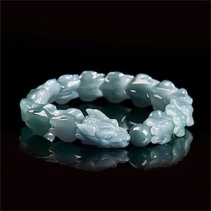 Puede incluir: Una pulsera de jade azul claro con tallas de cabeza de drag&oacute;n. La pulsera est&aacute; hecha de jade pulido y tiene una superficie reflectante. Las cabezas de drag&oacute;n est&aacute;n intrincadamente talladas y detalladas, con un acabado liso y brillante.