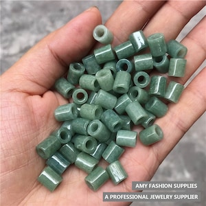 Pode incluir: Uma coleção de contas de jade verde, cada uma com um furo no centro, perfeitas para fazer joias.