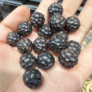 May include: A collection of 17 dark brown wooden beads with a textured, honeycomb-like surface. The beads are round and have a slightly irregular shape.