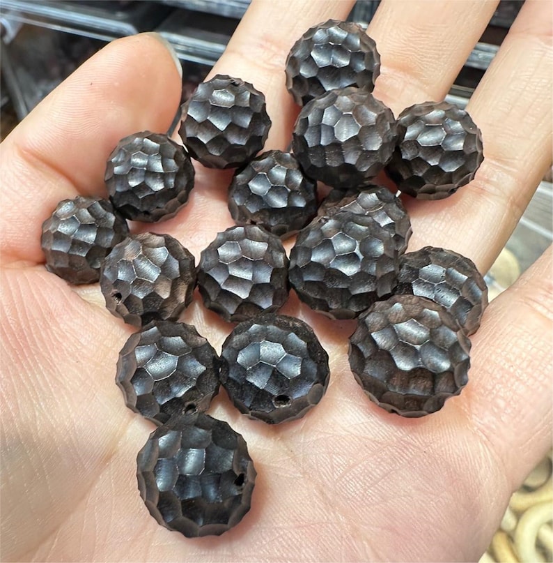 May include: A collection of 17 dark brown wooden beads with a textured, honeycomb-like surface. The beads are round and have a slightly irregular shape.
