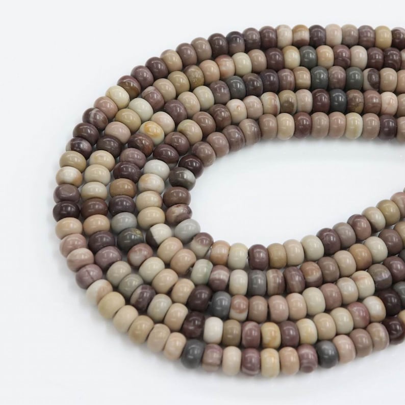 May include: A strand of brown, beige, and white gemstone beads. The beads are round and have a smooth, polished finish.