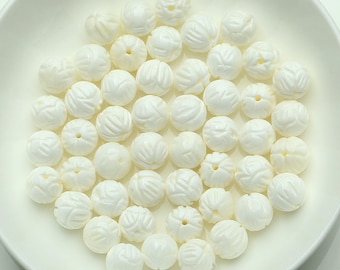 Puede incluir: Una colección de cuentas de concha blanca con un diseño floral tallado. Las cuentas son lisas y pulidas, y tienen un aspecto natural y orgánico.