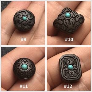 May include: Four wooden beads with intricate carvings and turquoise accents. Each bead has a unique design, including a swirl pattern, a floral design, and a geometric design. The beads are dark brown and have a smooth, polished finish.