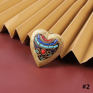 Puede incluir: Un medall&oacute;n de coraz&oacute;n dorado con un dise&ntilde;o de mosaico colorido. El medall&oacute;n tiene un patr&oacute;n azul, rojo y turquesa con un marco dorado.