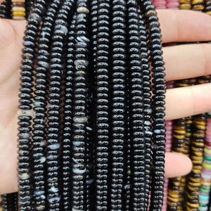 Pu&ograve; includere: Un filo di perle di agata nera con vortici bianchi e grigi. Le perle sono rotonde e hanno una forma leggermente irregolare. Le perle sono infilate su un filo elastico trasparente.