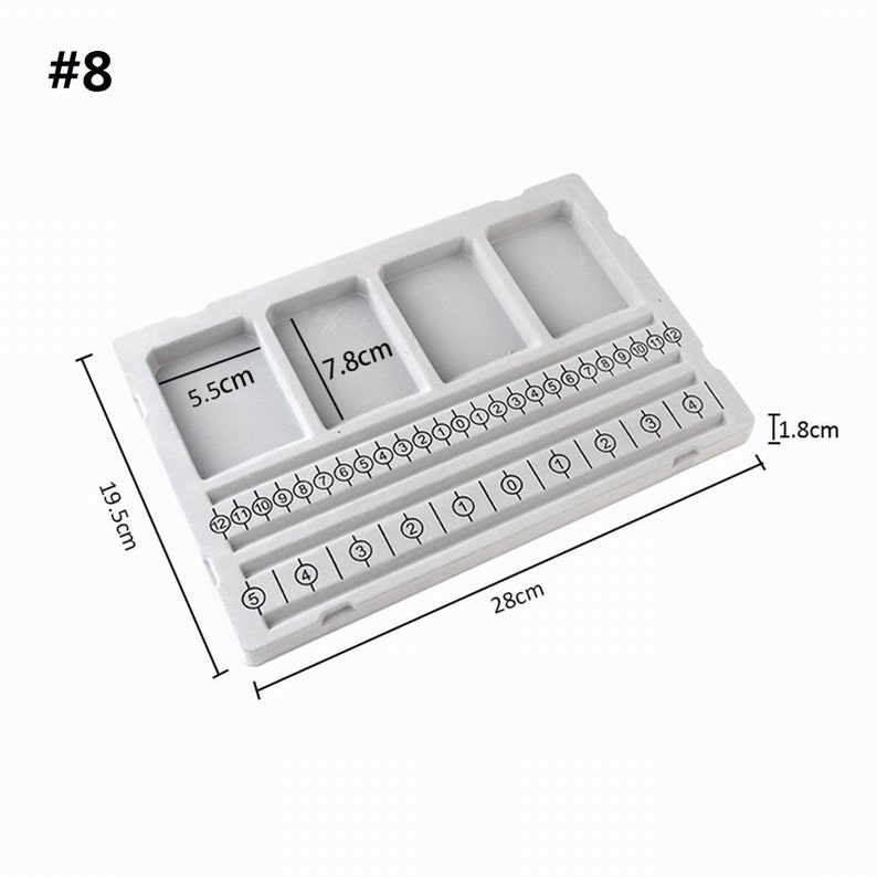 May include: A white plastic ring sizing tool with five compartments and a numbered sizing guide. The tool measures 19.5 inches long, 7.8 inches wide, and 1.8 inches tall.