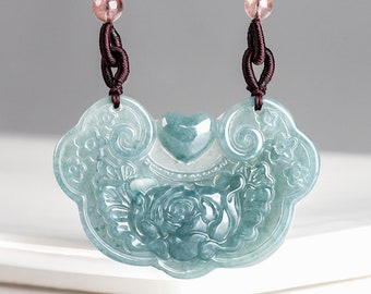 Puede incluir: Un collar con un colgante de jade tallado con un diseño floral y una forma de corazón. El colgante es de color verde claro y está unido a un cordón marrón con cuentas rosas.