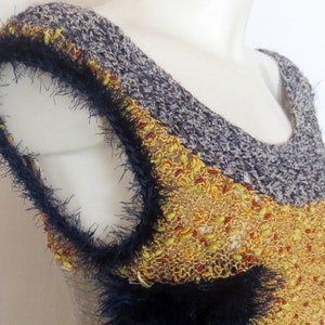 May include: A sleeveless top with a scoop neckline. The top features a color-blocked design with a gray knit upper section, a textured yellow and red mid-section, and a navy blue trim with a fuzzy texture. The garment is displayed on a mannequin.
