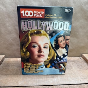 May include: A 100 Movie Pack Hollywood Classics DVD collection box set featuring 25 double-sided DVDs. The cover displays a portrait of Marilyn Monroe, a film strip graphic, and a list of actors including Frank Sinatra and Elizabeth Taylor.