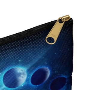 May include: A blue and black zippered pouch with a galaxy print and a gold YKK zipper pull. The pouch features a design of three glowing planets.