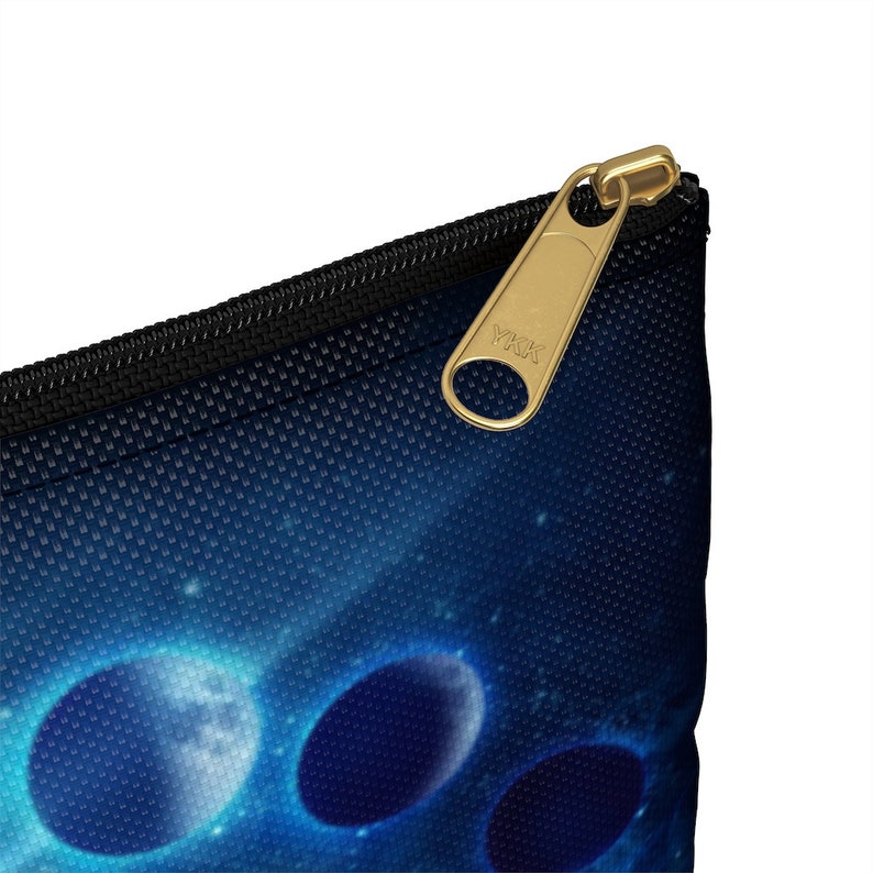 May include: A blue and black zippered pouch with a galaxy print and a gold YKK zipper pull. The pouch features a design of three glowing planets.