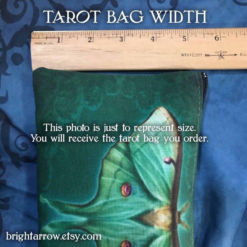 May include: A green tarot bag with a zipper closure and a moth design. The bag is measured with a ruler to show its width, which is 5 inches.