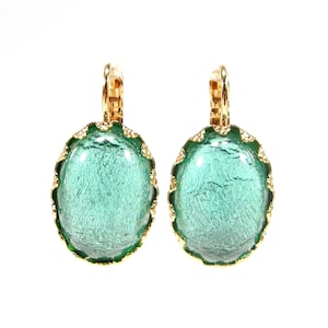May include: A pair of gold-tone earrings with a green glass oval-shaped stone set in a gold-tone frame.