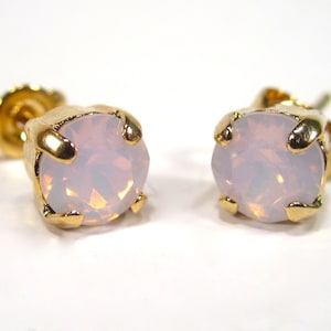 May include: A pair of gold stud earrings with a white opal stone in each earring.
