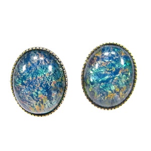 Puede incluir: Un par de pendientes redondos, azules y verdes con un engaste de metal dorado. Los pendientes tienen un acabado moteado e iridiscente.