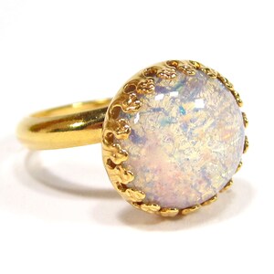 May include: A gold ring with a white opal stone set in a gold filigree design.
