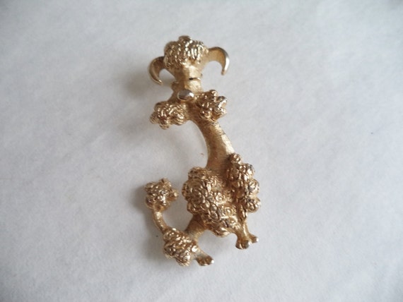 Designer signed Jomaz Goldtone poodle brooch wearing a crown and collar encrusted with crystal Textured metal fur detail.
