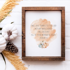 May include: A framed print with a rustic brown wooden frame. The print features the text "I will give thanks to the Lord with my whole heart. I will recount all of your wonderful deeds. Psalm 9:1." White pumpkins and pinecones are arranged around the frame.