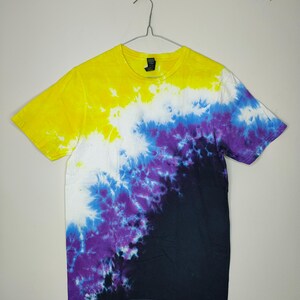Puede incluir: Una camiseta de manga corta con cuello redondo que presenta un patrón de teñido anudado que transiciona diagonalmente desde amarillo brillante en la parte superior, pasando por blanco y morado, hasta un negro oscuro sólido en el dobladillo.