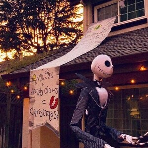 A house with a large Nightmare Before Christmas banner hanging from the second story window. A Jack Skellington statue is in the yard.