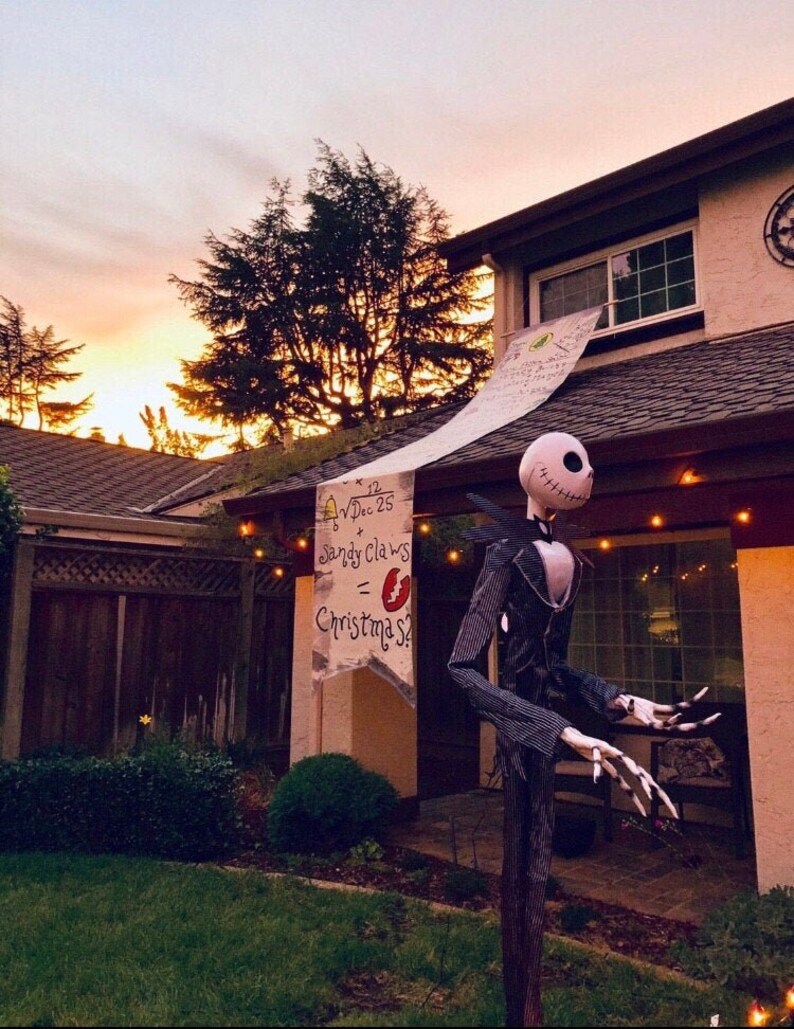 A house with a large Nightmare Before Christmas banner hanging from the second story window. A Jack Skellington statue is in the yard.