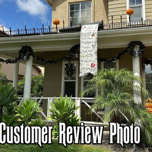 May include: A house decorated for Halloween and Christmas. A banner with the text "Good Cheer", "Mistletoe", "Sleigh Bells", "Dec 25", and "Sandy Claws = Christmas?" hangs from the roof. The house has pumpkins and Halloween decorations.